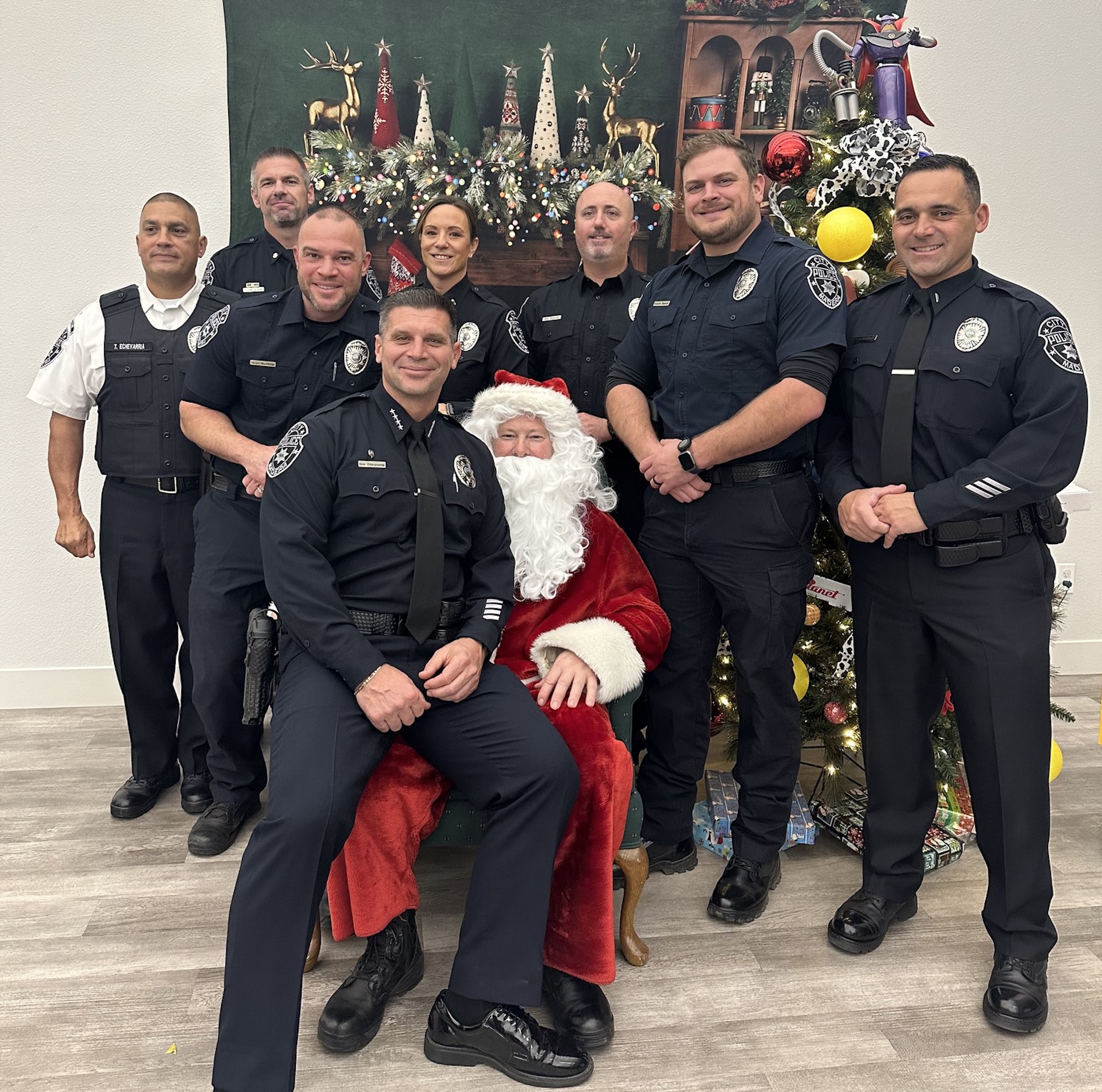 Police officers gather in front of a Christmas tree and pose with Santa
