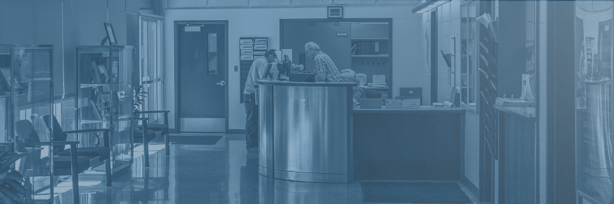 Photograph of City employee helping man at front desk inside of City Hall